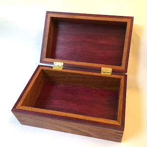 A photo of a small, handmade box with the top hinged open. It is made from jatoba and purplewood.