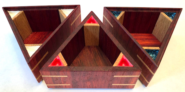A photo of three wooden triangular boxes made from padauk wood, with oak highlights.